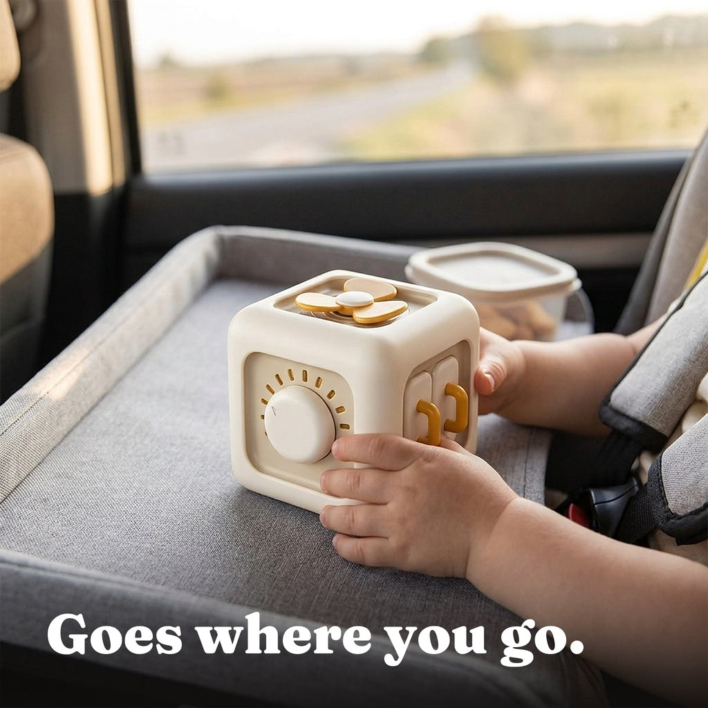 Toddler holding the Activity Cube on a car seat tray while travelling