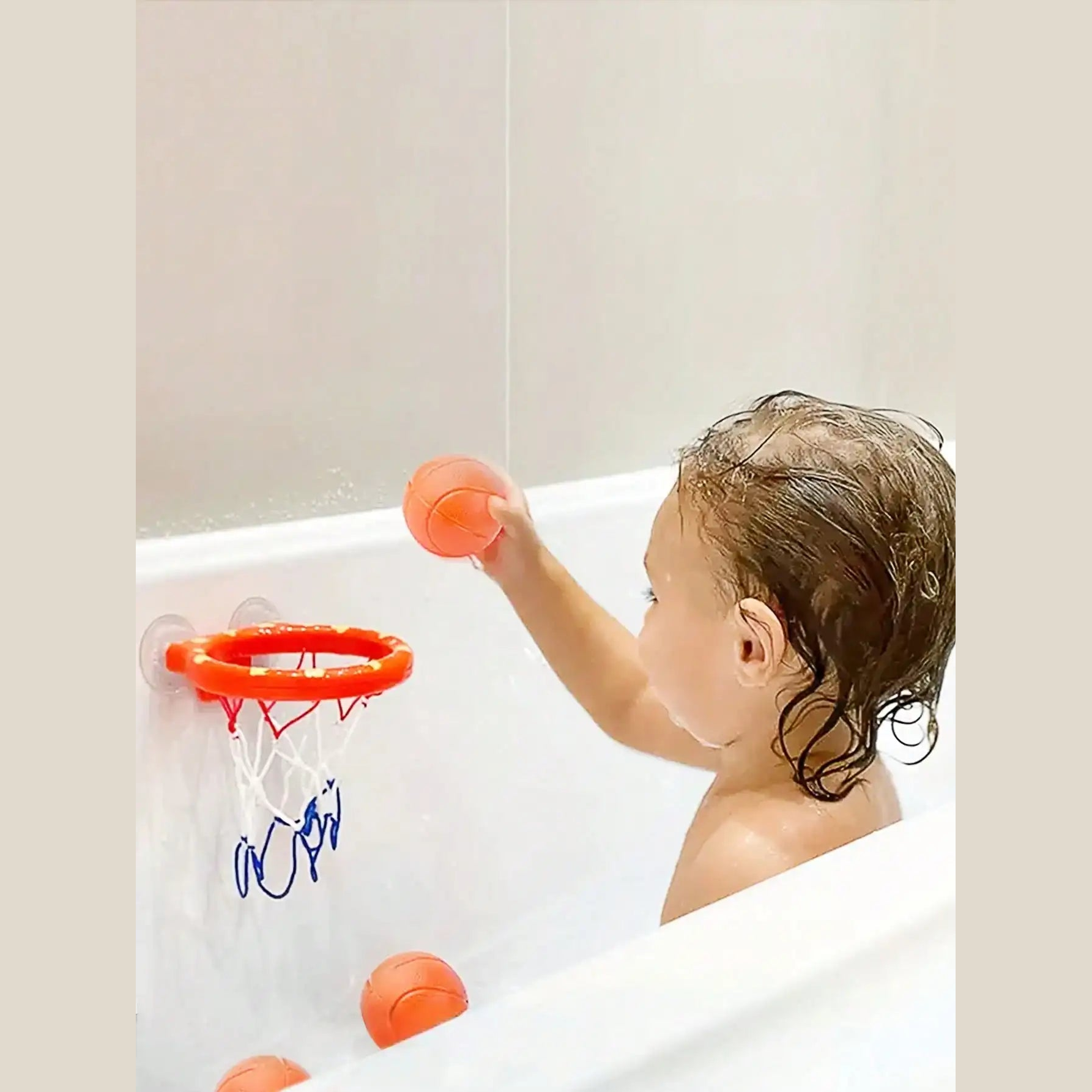 Child shooting a soft ball at the suction-cup bath basketball hoop